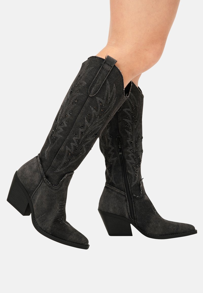 Botas de mezclilla negras de estilo western con punta afilada, altura hasta la mitad de la pantorrilla y costuras decorativas. Presentan un cierre lateral y tacón bajo en bloque.