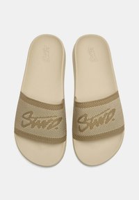 Sandali slip-on color cuoio con cinturino in mesh testurizzato con logo. La suola è piatta e liscia, garantendo una calzata confortevole.