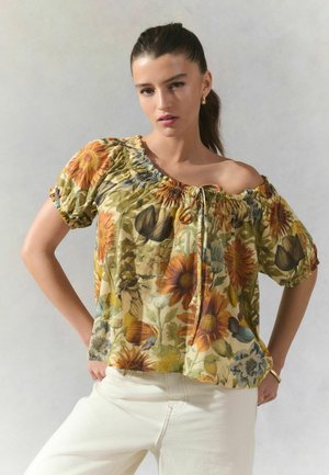 Blumige schulterfreie Bluse mit einem gelb-grünen Grundton, die Sonnenblumen und andere Blumen enthält, elastische Ärmel mit Bündchen und einem vorderen Bindetail.