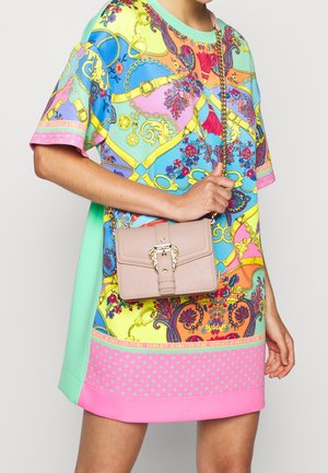 Kleurrijke oversized jurk met levendige patronen in blauw, roze en groen; voorzien van een roze handtas met kettingriem, een gestructureerd oppervlak en gouden accenten.