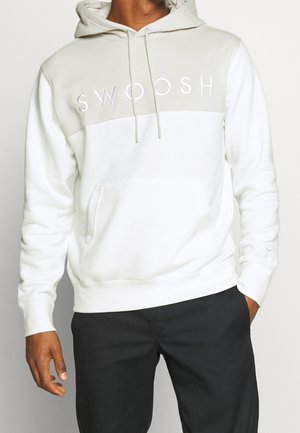 Felpa bianca con pannello superiore grigio; logo "SWOOSH" ricamato. Presenta una tasca frontale e cordini regolabili sul cappuccio.