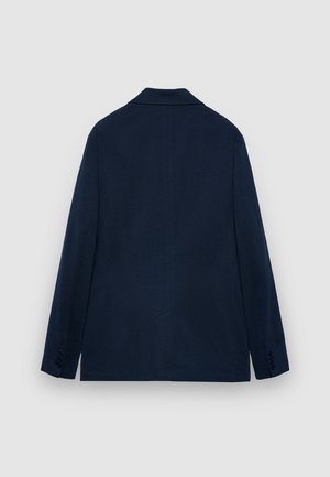 Giacca blu navy con una texture liscia, colletto a revers, maniche lunghe e sottili dettagli delle cuciture sul retro. Design semplice e su misura.