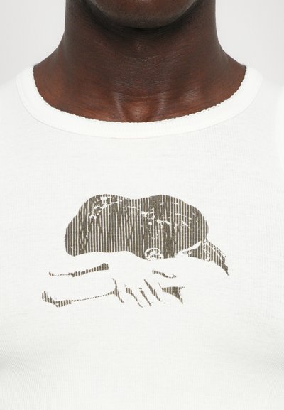 Weißes Baumwoll-Tanktop mit einem strukturierten braunen Grafikdruck von Händen und einem Hut, ergänzt durch feine vertikale Linien, die das Design detaillieren.