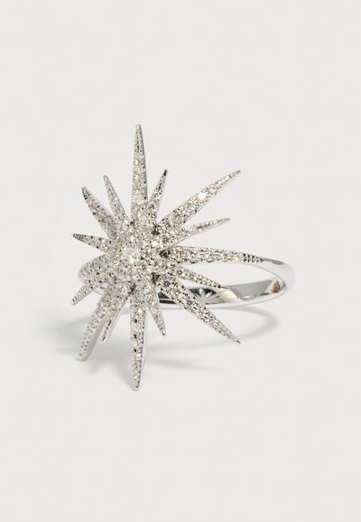 Bague en argent avec un design en éclat d'étoile comportant plusieurs pointes effilées incrustées de petites pierres scintillantes.