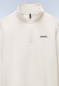Cream pullover with a high collar, half-zip front, and embroidered logo. Soft texture and smooth fabric, suitable for layering.