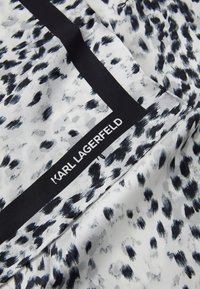 Tela de seda estampada en blanco y negro con motivos de pinceladas, con un borde negro y el logo "KARL LAGERFELD" en blanco.