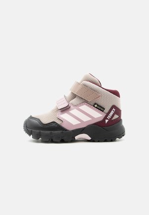 Beżowo-różowy dziecięcy but trekkingowy Gore-Tex z czarną podeszwą, rzepami oraz logo Terrex na pięcie.