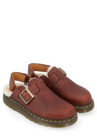 Bruine leren klompen met een gespdetail, zachte witte voering, een ronde neus en een rubberen zool met gele stikselaccenten.