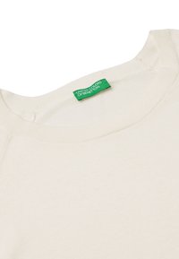 Cremfarbener Sweatshirt mit rundem Halsausschnitt. Mit einem grünen Etikett mit der Aufschrift "United Colors of Benetton" in der Nähe des Kragens. Weicher Stoff.