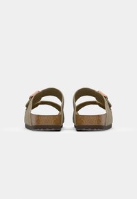 Sandale marron avec deux larges brides, dotée d'un accent de boucle. Fabriquée en matériau synthétique, avec une semelle plate et un footbed texturé.