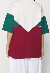 Färgdela t-shirt med vit överdel, gröna ärmar och vinröd nederdel med kontrasterande sömmar och avslappnad passform.