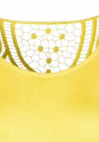 Žlutý top s hladkým povrchem a krajkovým zadním designem s hexagonálními vzory. Výstřih je kulatý, zdůrazňující živou barvu.