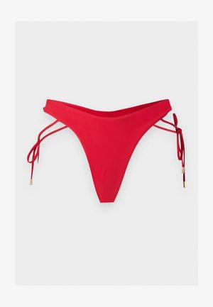 Bas de bikini rouge avec doubles bretelles latérales nouées en nœuds, avec des extrémités dorées, posé à plat sur un fond clair.