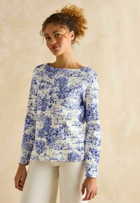 Weißes Langarmhemd mit Druck eines blauen Küstenszenario, das Boote und Palmen zeigt. Rundhalsausschnitt und bequeme Passform. Aus weichem Baumwoll-Mix.