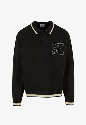 Fekete kötött póló fehér csíkos gallérral, díszes "K" folttal és csillagokkal a mellrészen. Bordás mandzsetta és szegély.