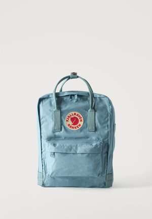 Jasnoniebieski plecak Fjallraven Kanken z przednią kieszenią, podwójnymi górnymi uchwytami i czerwonym okrągłym logo na jednolitym białym tle.