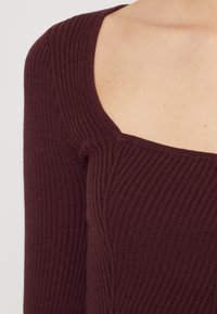 Bordowy prążkowany sweter z kwadratowym dekoltem i długimi rękawami, charakteryzujący się subtelną fakturą i dopasowanym krojem.