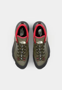 Olivgrüne Kletterschuhe mit schwarzen Sohlen, roten Akzenten und gelbspitzen Schnürsenkeln. Verfügt über ein strukturiertes Obermaterial und Branding an den Seiten.