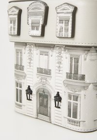 Boîte décorative en forme de façade de bâtiment blanc avec des fenêtres détaillées, des balcons et deux petites lanternes murales noires à l'avant.