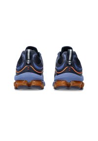 Blå sportskor med en texturerad meshöverdela, rund tå och orange detaljer vid hälen och sidorna; sulan har en flerskiktsdesign.