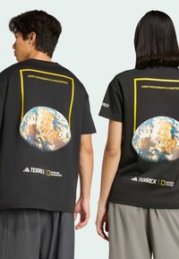 Black cotton t-shirt featuring a large globe graphic on the back, yellow border, and text "EVERY PHOTOGRAPH IS A MASTERPIECE." Logo accents included.