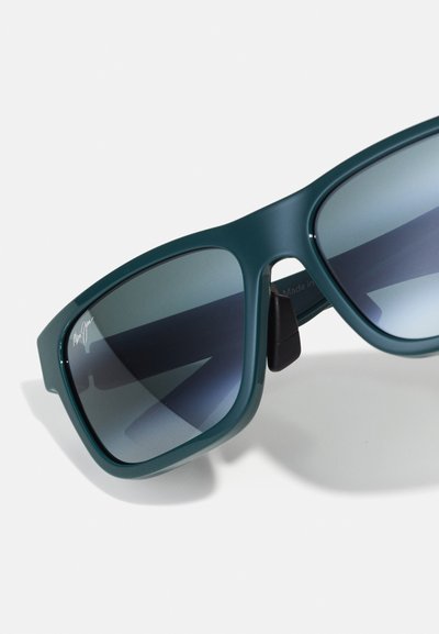 Teal plastic sunglasses with gray gradient lenses, featuring a square shape and black hinge accents. Notable brand logo on the frame.