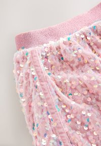 Shorts roses à sequins présentant un tissu doux texturé avec une large ceinture élastique. Ornés de sequins métalliques multicolores.