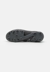 Suola di scarpa da ginnastica nera con gomma texturizzata, caratterizzata da un motivo antiscivolo, tacchetti di trazione e una sezione centrale liscia.