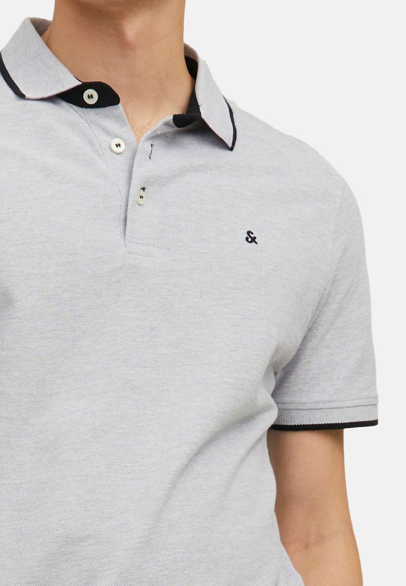 Lichtgrijs polo shirt met een zwarte kraag en manchetten, voorzien van een drieknopenssluiting en een klein geborduurd logo op de borst.