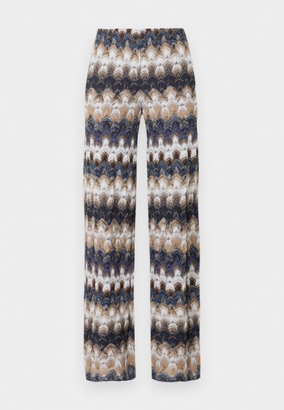 Παντελόνια με φαρδιά μπατζάκια και πολύχρωμο ζιγκ-ζαγκ μοτίβο σε αποχρώσεις του μπλε, μπεζ, καφέ και λευκού, τοποθετημένα επίπεδα σε φωτεινό φόντο.