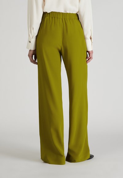 Groene wijde broek met elastische tailleband, voorzien van een gladde textuur en een vloeiende stijl, gecombineerd met een lichtgekleurde blouse.