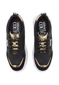 Baskets noires avec accents dorés, présentant une tige en cuir texturé, un col rembourré, une semelle blanche et un intérieur marqué.