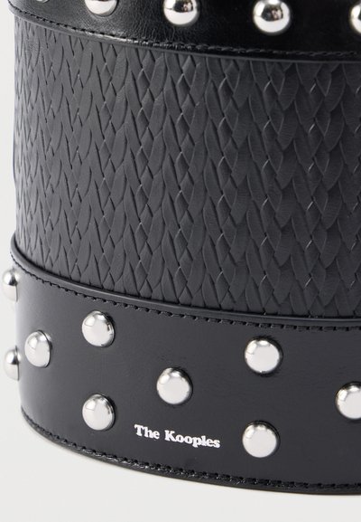 Μαύρο δερμάτινο προϊόν με υφαντό υφή, ασημένιες καρφίτσες και σήμανση. Διαθέτει λείο λουράκι με γυαλιστερό φινίρισμα και ανάγλυφες λεπτομέρειες.