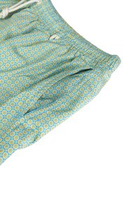 Pantaloni corti azzurri con un motivo di cerchi gialli e bianchi. Presentano una vita elastica con cordino e una texture di tessuto morbido.