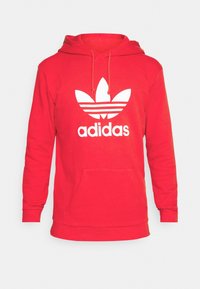 Roter Baumwollhoodie mit Kängurutasche, Zugbandkapuze und großem weißen Adidas-Logo mit drei Streifen und einem Trefoil-Design.
