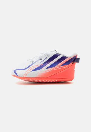 Scarpa da corsa bianca e arancione neon con strisce grafiche viola e arancioni, lacci e una linguetta sul tallone su uno sfondo semplice.