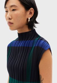 Top sin mangas con pliegues que presenta rayas verticales en navy, verde y azul. Escote alto con una tela texturizada y un diseño limpio.