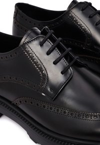 Zwarte leren dress shoes met een brogue ontwerp, gladde textuur en platte veters. Opvallende perforaties en stiksels langs de randen.