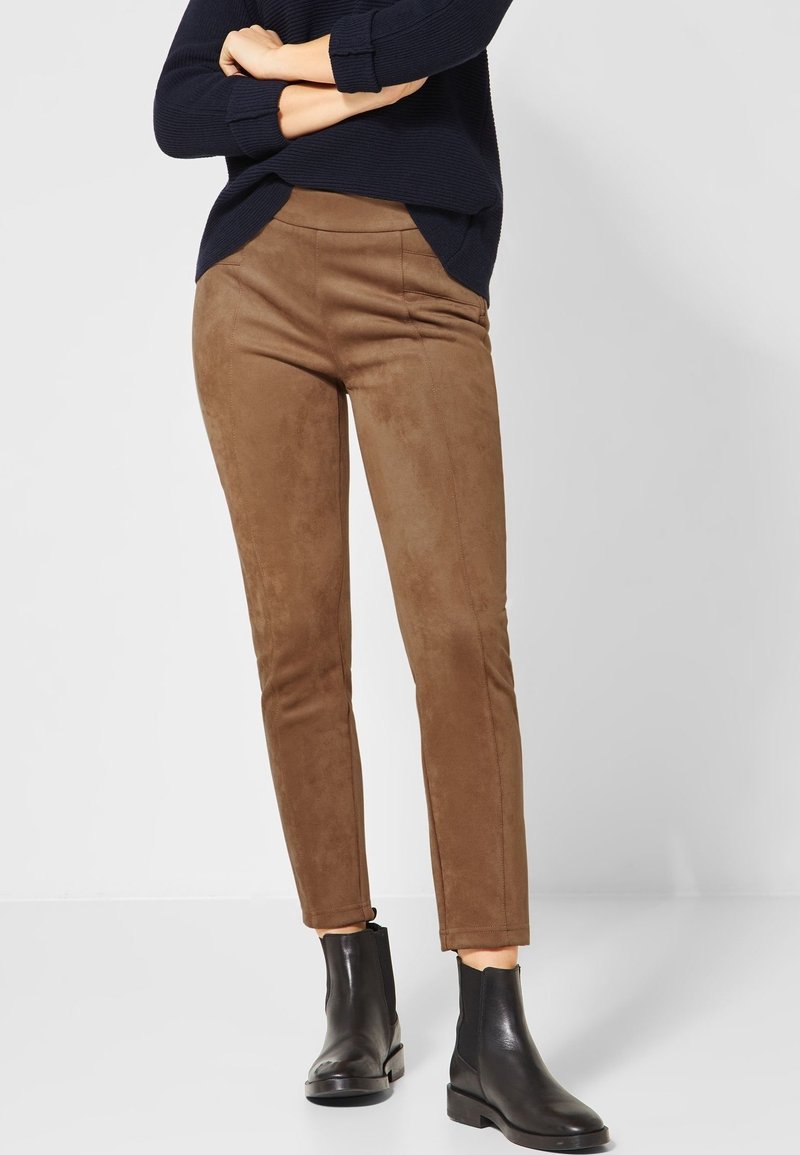 Bruna faux suede byxor med skräddarsydd passform, försedd med sidfickor och en slät yta, kombinerat med svarta ankelstövlar.