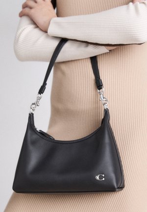 Sac à main en cuir noir avec une silhouette courbée, des accessoires en métal argenté et une courte bandoulière réglable. Présente un accent logo et une texture lisse.