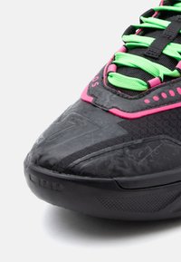 Czarny but sportowy z teksturowanym syntetycznym wierzchem, różowymi akcentami, zielonymi sznurówkami oraz trwałą gumową podeszwą z wzorzystymi detalami.