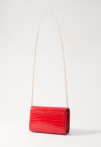 Borsa a mano in finta pelle di coccodrillo rossa con una forma rettangolare elegante. Presenta una tracolla in catena dorata e una finitura lucida.