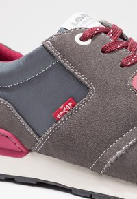 Graue Wildleder- und Stoff-Sneaker mit burgunderfarbenen Akzenten, weißer Naht und rotem Markenlabel. Verfügt über eine gepolsterte Sohle und strukturierte Details.