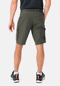 Cargo-Shorts in Olivgrün, aus leichtem Stoff gefertigt. Mit Seitentaschen und lockerer Passform, kombiniert mit dunklen Sneakers und weißen Socken.