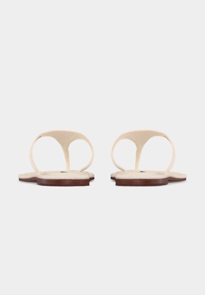 Επίπεδα μπεζ σανδάλια με λεπτά λουράκια και ξύλινες σόλες, ορατά από πίσω σε λευκό φόντο.