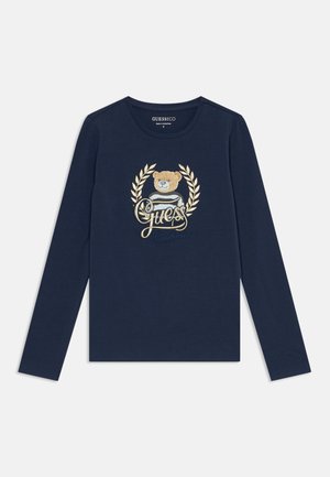 Chemise bleu marine à manches longues avec un ours en peluche portant un pull rayé, une couronne de laurier dorée et le texte "Guess California" sur le devant.