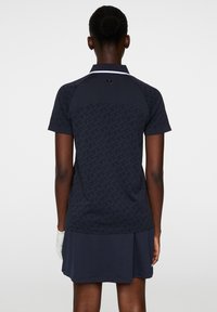 Navy Polo-Kleid mit kurzen Ärmeln, strukturierter Oberseite, weißem Kragen und schichtigem Rock. Verfügt über ein geprägtes Design auf der Rückseite.