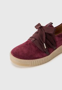 Suedesneakers i bordeaux med en tekstureret overflade, der har stofsnørebånd bundet i en sløjfe, og en gummiplatformssål med lodrette riller.