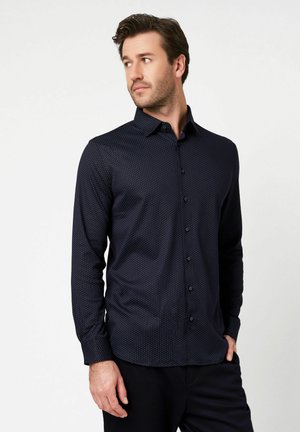 Langärmeliges dunkelblaues Hemd mit einem dezenten Polka-Dot-Muster, Button-Down-Kragen und vorderer Knopfleiste, hergestellt aus glattem Stoff.