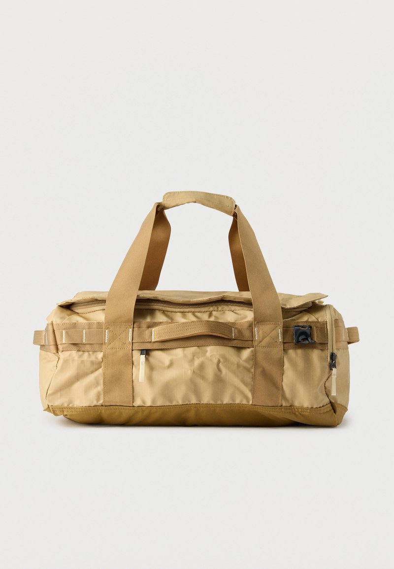 Μπεζ ορθογώνια τσάντα duffel με δύο κοντά χερούλια, μπροστινή τσέπη με φερμουάρ και ανθεκτικές ιμάντες νάιλον σε απλό φόντο.